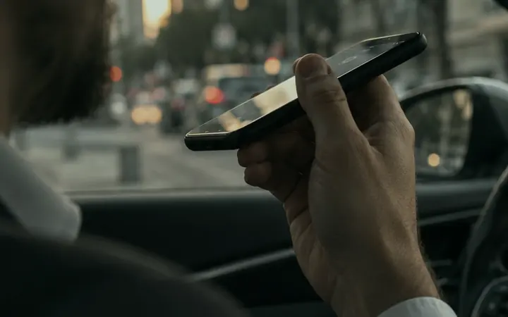 Vendedor dentro do carro, entre duas visitas, segurando o celular